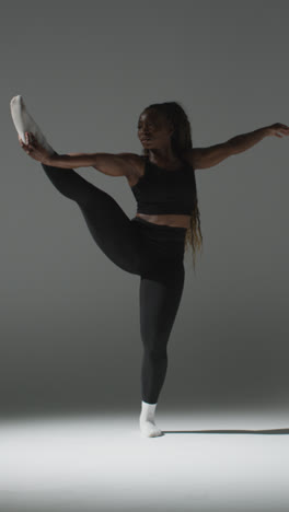 Vertical-Video-Full-Length-Studio-Shot-Of-Woman-Wearing-Gym-Fitness-Clothing-Doing-Stretching-Exercise